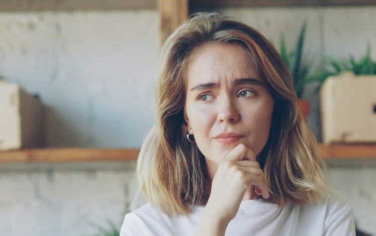 Woman placing her hand on the chin, wondering if dermal fillers will change the way she looks.